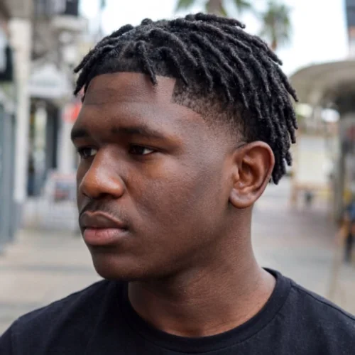 Black man with dreadlocks and a low taper fade haircut