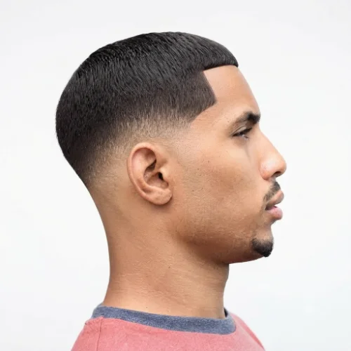 Man with messy textured hair and a low taper fade blowout featuring relaxed volume on a white background.
