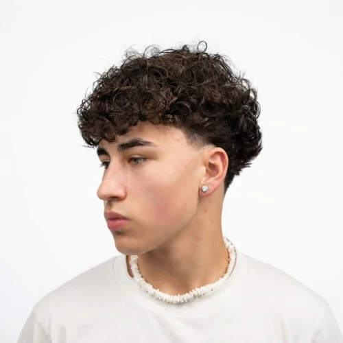 Man with curly hair styled into a low taper fade blowout featuring natural curls and volume on a white background.
