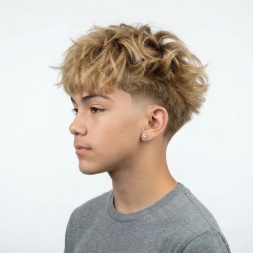 Man with blonde hair styled into a low taper fade blowout featuring textured volume on a white background.
